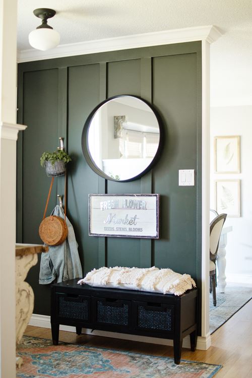 Emerald green board and batten full wall entryway with round mirror and bench 