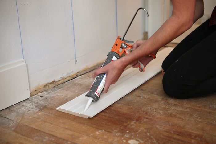 Applying caulk to shiplap board