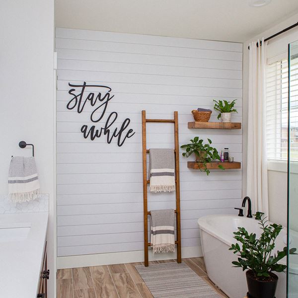 White shiplap bathroom accent wall with stay awhile farmhouse decor
