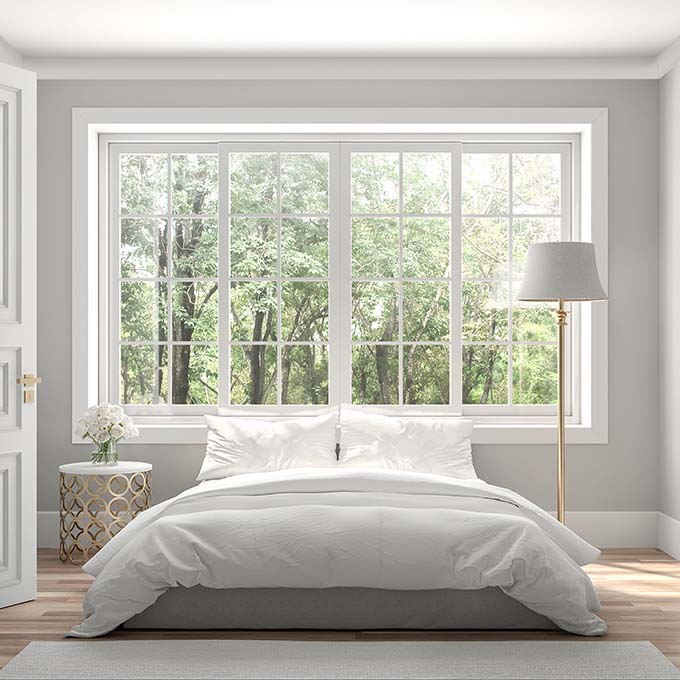 Bedroom with bed in front of large window trimmed out in premium primed trim 